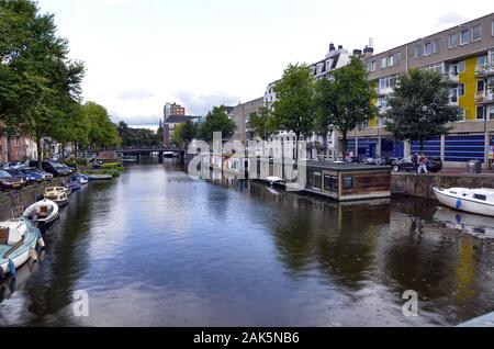 Amsterdam,Hollande,Août 2019. Dans le centre historique une vue qui est un symbole de la ville : une péniche brun amarré au bord du canal. Derrière je Banque D'Images