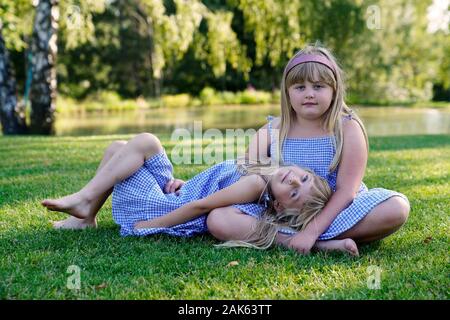 Deux jeunes filles, frères et soeurs assis sur le pré, 6 et 7 ans, portrait, République Tchèque Banque D'Images