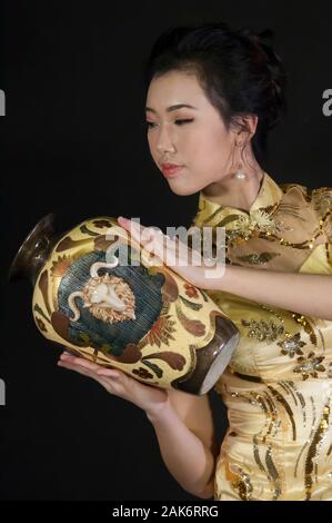 Tête et épaules de femme d'origine asiatique, vêtu du costume traditionnel chinois qipao cheongsam ou un style traditionnel Banque D'Images
