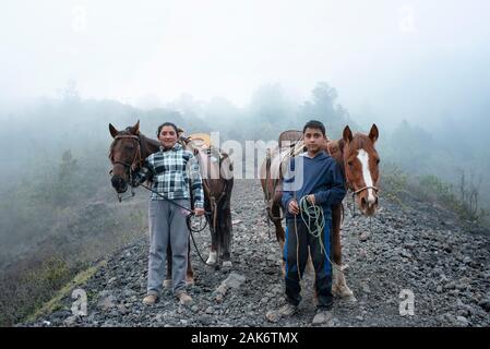 Portrait de l'environnement d'un garçon et de sa mère. La famille locale offrant l'équitation pour les touristes sur le terrain volcanique autour de volcan Pacaya, Guatemala Banque D'Images