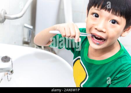 Petit garçon asiatique avec une brosse à dents nettoyer les dents dans la salle de bains. Close up kid se brosser les dents. soins de santé et l'hygiène dentaire concept. Banque D'Images