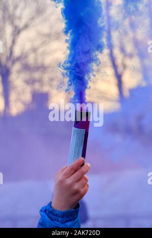 La main est titulaire d'un artifice avec une fumée de la couleur du bleu. Close up. Banque D'Images
