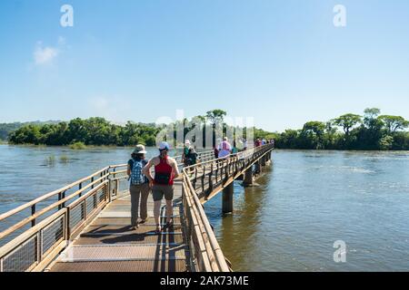 Les touristes la marche sur la passerelle suspendue menant à la Gorge du Diable, la plus grande cascade de l'Iguazu Falls Banque D'Images