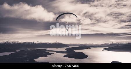 Vue panoramique du parapente sur le lac Nahuel Huapi et les montagnes de Bariloche en Argentine, avec des pics escarpés en arrière-plan en noir et blanc Banque D'Images