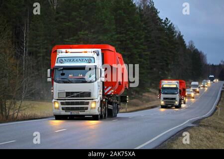 Deux camions Volvo FH blanc en charge de Nikkanen surdimensionnée transport sur route rurale sur une soirée d'hiver. Salo, Finlande. Le 30 décembre 2019. Banque D'Images