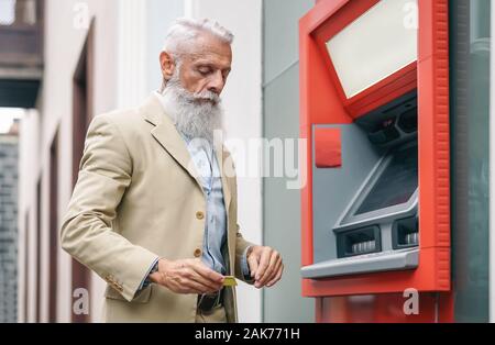 Man retirer de l'argent à un distributeur automatique de banque avec carte de débit - mature hipster barbu mâle qui fait les paiements par carte de crédit dans un distributeur automatique Banque D'Images