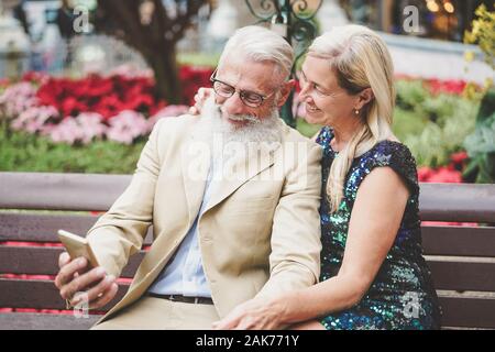 Happy senior couple regardant sur mobile smartphone outdoor - Mature retraités de la mode s'amuser grâce à la nouvelle technologie cellphones apps Banque D'Images