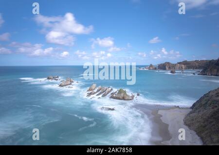 Rivage rocheux avec des vagues pastel douces et des formations accidentées le long de la côte basque du nord de l'Espagne. Banque D'Images