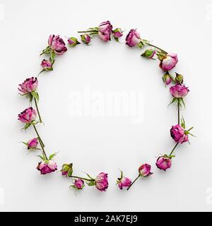 Cadre rond ou couronne faite de roses roses séchées sur blanc. Modèle de création et les jours fériés. Banque D'Images