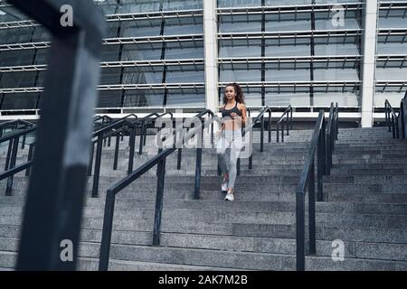 Plan large de jeune femme athlétique en marche en bas, la formation au stade municipal urbain Banque D'Images