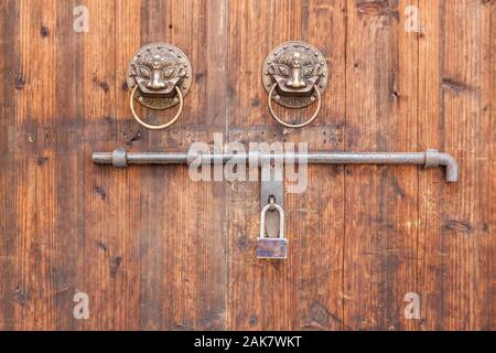 Porte en bois traditionnel chinois avec talisman et heurtoirs de bronze cadenas. Banque D'Images