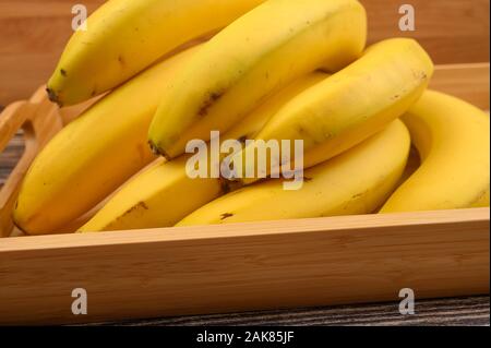 Bande de bananes jaunes mûrs sur un plateau en bois sur un fond de bois. Close up Banque D'Images