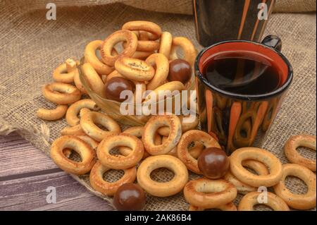 Bagels, petits chocolats, une tasse de thé et un tissu de fabrication locale sur un fond de bois close-up Banque D'Images