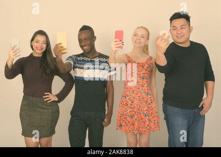 Studio shot of happy groupe diversifié de multi ethnic friends smiling tout en prenant des photos avec des téléphones portables selfies ensemble Banque D'Images