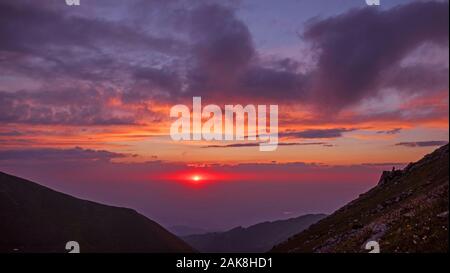 Coucher du soleil dans les montagnes : soleil sur l'horizon illumine les nuages ; dernière lumière de jour en jour Banque D'Images