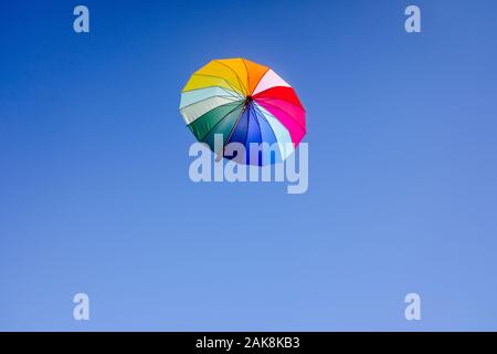 Un simple parapluie multicolores flottent dans l'air, isolé fond de ciel bleu. Banque D'Images