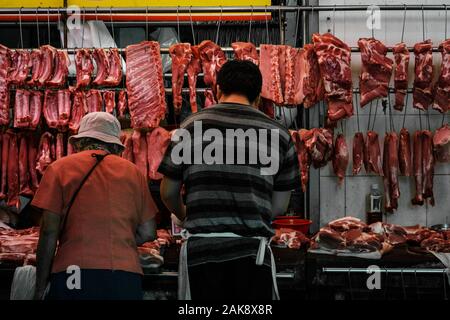 Hong Kong, Chine - Novembre 2019 : Butcher et le client l'achat et la vente de viande sur street market store à Hong Kong Banque D'Images