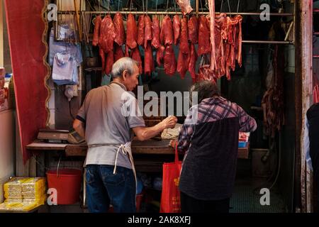 Hong Kong, Chine - Novembre 2019 : boucher vendant de la viande de femme plus âgée sur street market store à Hong Kong Banque D'Images