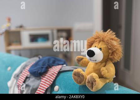 Jouet ours Pluff forme bonjour assis sur un canapé sur fond gris Banque D'Images