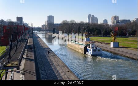 PARIS, FRANCE - 6 janvier 2020 : une barge fluviale motorisée acier circule sur le canal de l'Ourcq au Parc de la Villette, à l'heure d'hiver. Banque D'Images