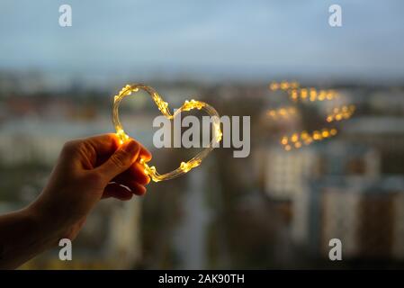 Coeur fait de petites lumières dans la main femme Banque D'Images