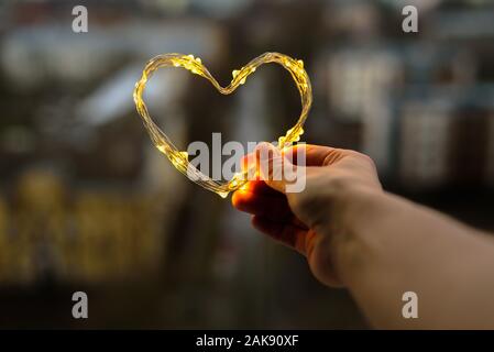 Coeur fait de petites lumières dans la main femme Banque D'Images