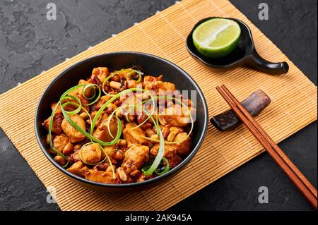 Poulet Kung Pao ou Gong Bao Ji Ding à fond dark slate. Sichuan Kung Pao est la cuisine chinoise plat avec la viande de poulet, piments, arachides, sa Banque D'Images