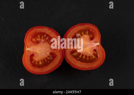 La moitié de la tomate. Tranches de tomate fraîche sur noir. Vue d'en haut. Banque D'Images