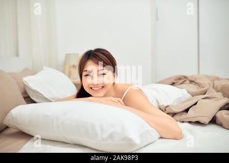 Asian woman stretching in bed après service de réveil, vue arrière Banque D'Images