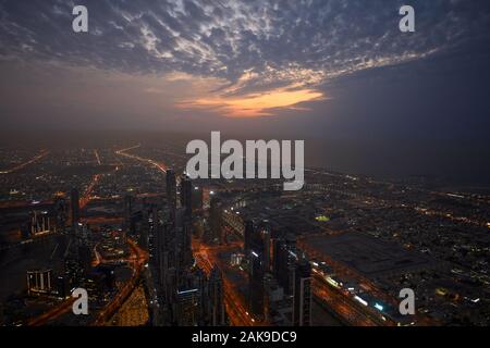 Dubaï, Émirats arabes unis - le 19 novembre 2019 - Dubaï ville illuminée high angle view avec des gratte-ciel dans un ciel nuageux soir Banque D'Images