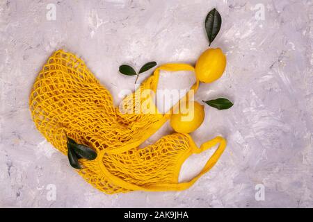 Les citrons en jaune string mesh sac réutilisable sur la table Banque D'Images