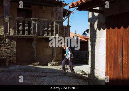 Combarro, province de Pontevedra, Galice, Espagne : A senior woman promenades dans la vieille ville traditionnelle de Combarro village de pêcheurs. Banque D'Images