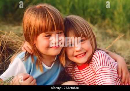 filles jumelles de trois ou quatre ans embrassant et souriant Banque D'Images