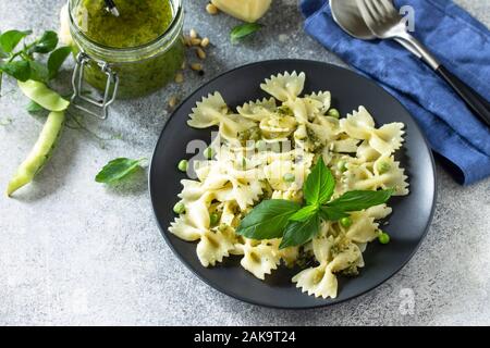 La cuisine Italienne en bonne santé. Pâtes aux petits pois et sauce pesto dans bol noir sur fond noir en gris. Espace libre pour votre texte. Banque D'Images