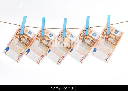 Les billets en euros sont fixés avec des pinces à linge bleu à une corde sur un fond blanc Banque D'Images