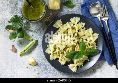 La cuisine Italienne en bonne santé. Pâtes aux petits pois et sauce pesto dans bol noir sur fond noir en gris. Vue supérieure de la télévision. Banque D'Images