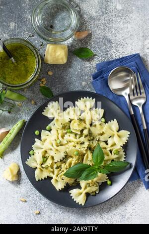 La cuisine Italienne en bonne santé. Pâtes aux petits pois et sauce pesto dans bol noir sur fond noir en gris. Vue supérieure de la télévision. Banque D'Images