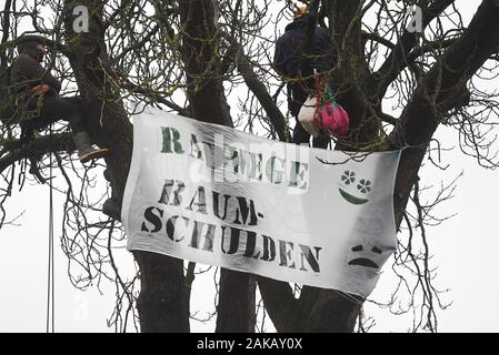 08 janvier 2020, Mecklembourg-Poméranie-Occidentale, Neunkirchen : avec un arbre à l'occupation de la route district K 5, d'activistes de l'environnement avec des banderoles avec l'inscription 'Radwege, Baumschulden" (pistes cyclables, dettes) près de Greifswald protester contre l'abattage des travaux pour l'extension de la côte de la mer Baltique. Les militants du mouvement pour la justice climatique Greifswald veulent attirer l'attention sur les résidus des plantes de la zone Vorpommern-Greifswald. Selon le mouvement pour la justice climatique, il y a un manque de plus de 4 000 arbres le long des routes de district dans le district de Vorpommern Banque D'Images