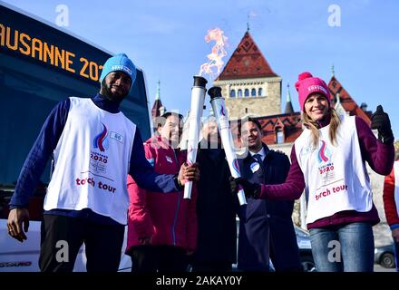 (200108) -- LAUSANNE, le 8 janvier 2020 (Xinhua) -- le porteur de flambeau Martina Kocher (1e R) reçoit le flambeau de Isaac Mukoma (1re L) au cours d'un relais de la flamme pour les Jeux Olympiques d'hiver de la jeunesse 3ème à Lausanne, Suisse, le 8 janvier 2020. (Xinhua/Lu Yang) Banque D'Images