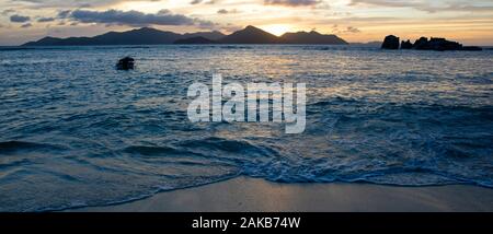 Paysage avec plage et mer en vertu de moody sky au coucher du soleil avec l'île de Praslin qui se profile en arrière-plan, La Digue, Seychelles Banque D'Images