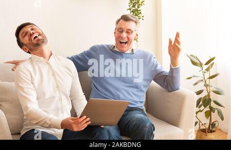 Man et sa maturité son rire passer du temps ensemble et s'amuser assis sur un canapé à la maison. Banque D'Images
