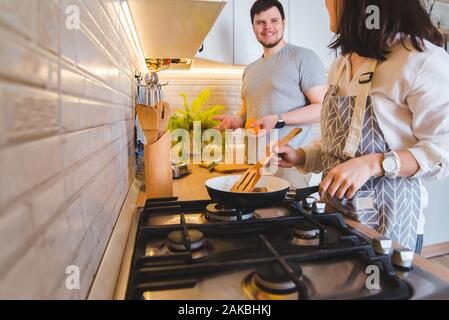 Couple cooking ensemble à la cuisine. faire frire les crêpes orange coupe Banque D'Images