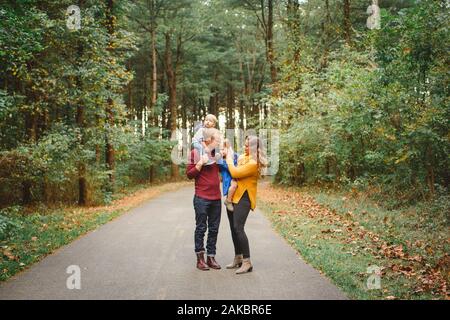 Portrait de famille aimante debout ensemble sur un chemin bordé d'arbres Banque D'Images