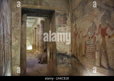 L'Égypte, de la Haute Égypte, vallée du Nil, Dendérah, temple guard assis dans la chapelle du temple d'Hathor avec les muses ornée de bas-reliefs Banque D'Images