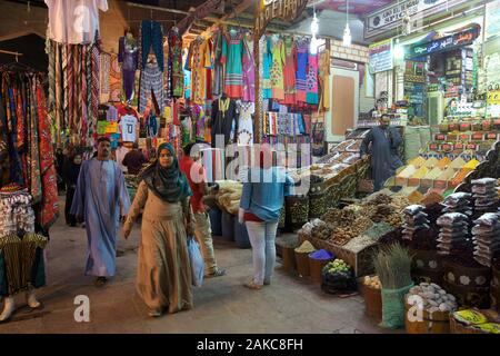 L'Égypte, de la Haute Égypte, Assouan, Les Égyptiens l'errance entre les peuplements d'épices et de vêtements colorés dans une allée couverte du souk Banque D'Images