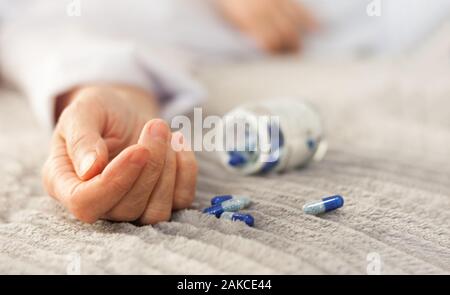 Woman's hand fermer par se suicider par une surdose de médicaments, pilules et bouteille à côté. (Ita) comprimés et l'addict concept background Banque D'Images