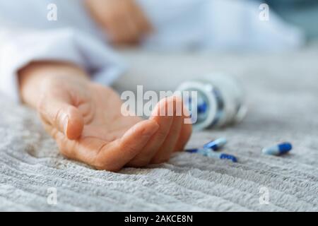 Woman's hand fermer par se suicider par une surdose de médicaments, pilules et bouteille à côté. (Ita) comprimés et l'addict concept background Banque D'Images