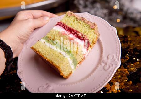 Brillant d'or gâteau savoureux est coupé en morceaux. Une tranche de gâteau sur une plaque rose. La cuisson à la maison pour une fête pour les enfants. Banque D'Images