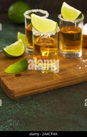 Or mexicain Tequila shot avec de la chaux et du sel sur la pierre sombre arrière-plan. Banque D'Images