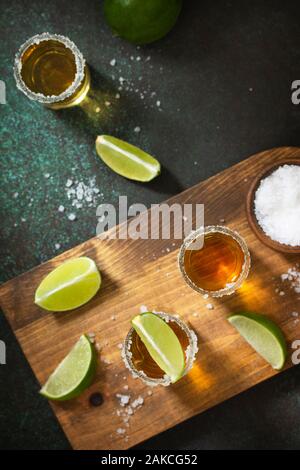 Or mexicain Tequila shot avec de la chaux et du sel sur la pierre sombre arrière-plan. Vue supérieure de la télévision mise de fond. Copier l'espace. Banque D'Images